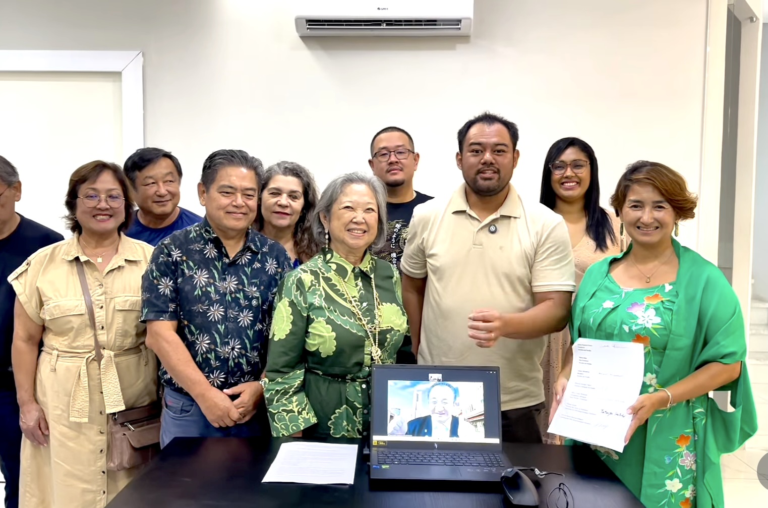 25日の署名時の記念写真、ノートパソコンの画面にはリモート出席した齋藤理事長