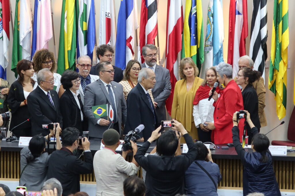 謝罪の瞬間。左側に並ぶ宮城あきらさんや奥原マリオ純さん、沖縄県人会の皆さんら申請者に向かって、謝罪の言葉を述べるエネア・アルメイダ委員長