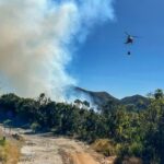 丘陵地帯の消火活動のために水を運ぶヘリコプター（©Corpo de Bombeiros RJ/Divulgacao）